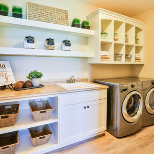 Inspiration för mellanstora moderna linjära grovkök, med en nedsänkt diskho, öppna hyllor, vita skåp, laminatbänkskiva, beige väggar, ljust trägolv och en tvättmaskin och torktumlare bredvid varandra