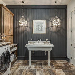 Immagine di una grande sala lavanderia tradizionale con ante con riquadro incassato, ante in legno scuro, pareti grigie, lavatrice e asciugatrice affiancate, pavimento marrone, lavatoio, top in granito, pavimento in gres porcellanato e top multicolore