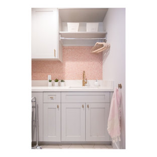 Foto di una sala lavanderia eclettica di medie dimensioni con lavello sottopiano, ante in stile shaker, ante grigie, top in quarzo composito, paraspruzzi rosa, paraspruzzi con piastrelle in ceramica, pareti bianche, pavimento in gres porcellanato, lavatrice e asciugatrice affiancate, pavimento bianco e top bianco