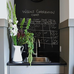 Inspiration för en vintage parallell tvättstuga, med en nedsänkt diskho, luckor med infälld panel, laminatbänkskiva, svarta väggar, en tvättpelare och grå skåp