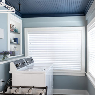 Cette photo montre une buanderie linéaire chic multi-usage avec un mur bleu, un sol en carrelage de porcelaine, des machines côte à côte, un sol marron, un plafond en bois et du lambris.