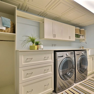 Inspiration for a large timeless single-wall porcelain tile and beige floor dedicated laundry room remodel in Montreal with beige cabinets, a farmhouse sink, blue walls, shaker cabinets, quartz countertops, a side-by-side washer/dryer and beige countertops