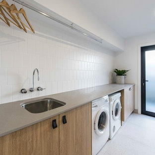 Photo of a contemporary single-wall dedicated laundry room in Brisbane with an undermount sink, medium wood cabinets, white walls, ceramic floors, a side-by-side washer and dryer, flat-panel cabinets, grey floor and beige benchtop.