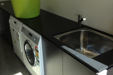 Einzeilige, Mittelgroße Moderne Waschküche mit Ausgussbecken, Laminat-Arbeitsplatte und Waschmaschine und Trockner nebeneinander in Brisbane