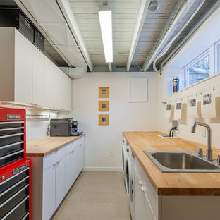Idéer för ett mellanstort industriellt parallellt grovkök, med en nedsänkt diskho, släta luckor, vita skåp, träbänkskiva, vita väggar och en tvättmaskin och torktumlare bredvid varandra