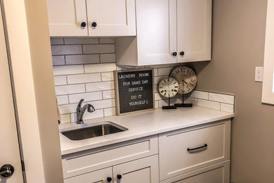 Example of a mid-sized transitional galley ceramic tile and brown floor dedicated laundry room design in Other with an undermount sink, shaker cabinets, white cabinets, quartzite countertops, white backsplash, subway tile backsplash, gray walls, a side-by-side washer/dryer and white countertops