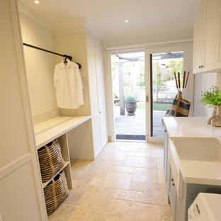 Esempio di una lavanderia contemporanea con lavello stile country, ante in stile shaker, ante blu, top in quarzo composito, pareti beige e pavimento in travertino