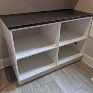 Inspiration för en mellanstor funkis svarta linjär svart tvättstuga enbart för tvätt, med en allbänk, släta luckor, vita skåp, laminatbänkskiva, svarta väggar, ljust trägolv och en tvättmaskin och torktumlare bredvid varandra