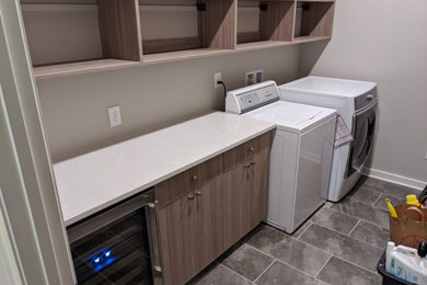 Design ideas for a large modern single-wall utility room in Birmingham with flat-panel cabinets, medium wood cabinets, quartz worktops, beige walls, ceramic flooring, a side by side washer and dryer, grey floors and white worktops.