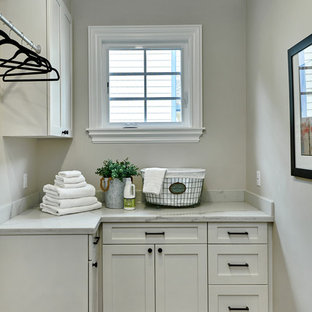 Immagine di una piccola sala lavanderia mediterranea con ante in stile shaker, ante bianche, top in quarzo composito, pareti grigie, pavimento in gres porcellanato, lavatrice e asciugatrice affiancate, pavimento rosso e top bianco