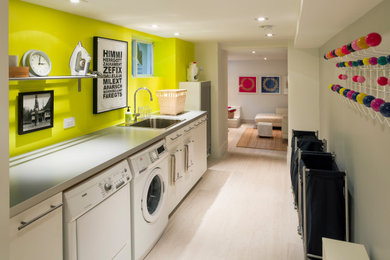 Diseño de cuarto de lavado lineal contemporáneo con fregadero sobremueble, encimera de cuarzo compacto, paredes amarillas, suelo de madera clara, lavadora y secadora juntas, suelo beige y encimeras grises