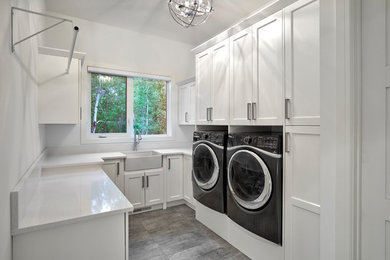 Utility room - large craftsman u-shaped ceramic tile and gray floor utility room idea in Other with a farmhouse sink, recessed-panel cabinets, white cabinets, quartz countertops, white walls and a side-by-side washer/dryer