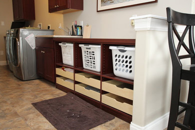 Inspiration for a small galley utility room in Philadelphia with a built-in sink, recessed-panel cabinets, dark wood cabinets, laminate countertops, beige walls, vinyl flooring and a side by side washer and dryer.