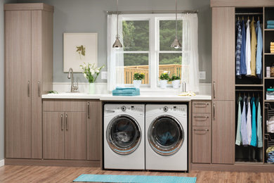 Inspiration för mellanstora industriella linjära tvättstugor enbart för tvätt, med en nedsänkt diskho, släta luckor, en tvättmaskin och torktumlare bredvid varandra, grå väggar, ljust trägolv och grå skåp