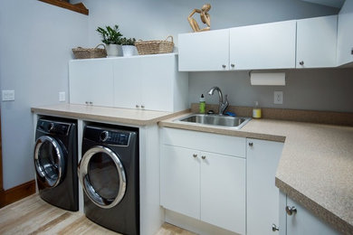Example of a large transitional l-shaped ceramic tile and beige floor dedicated laundry room design in Cincinnati with flat-panel cabinets, white cabinets, laminate countertops, white walls, a side-by-side washer/dryer, a drop-in sink and beige countertops