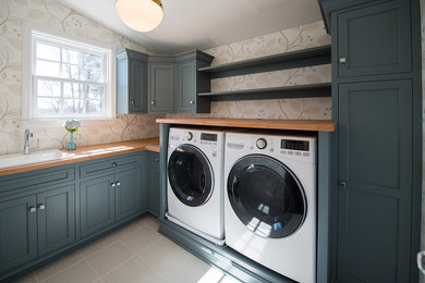 Example of a transitional l-shaped porcelain tile dedicated laundry room design in Philadelphia with a drop-in sink, blue cabinets, wood countertops, multicolored walls, a side-by-side washer/dryer and recessed-panel cabinets