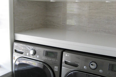 Ispirazione per una lavanderia contemporanea di medie dimensioni con lavello sottopiano, ante in stile shaker, ante bianche, top in superficie solida, lavatrice e asciugatrice affiancate e pareti grigie