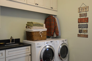 シカゴにあるお手頃価格の中くらいなトランジショナルスタイルのおしゃれな家事室 (ll型、アンダーカウンターシンク、シェーカースタイル扉のキャビネット、白いキャビネット、御影石カウンター、緑の壁、クッションフロア、左右配置の洗濯機・乾燥機、グレーの床、黒いキッチンカウンター) の写真
