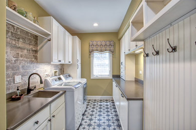 Design ideas for a medium sized traditional galley utility room with a submerged sink, recessed-panel cabinets, white cabinets, composite countertops, ceramic flooring, a side by side washer and dryer and multi-coloured floors.