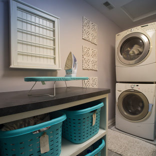 Foto di una sala lavanderia chic di medie dimensioni con nessun'anta, top in superficie solida, pareti viola, pavimento in vinile, lavatrice e asciugatrice a colonna e pavimento grigio