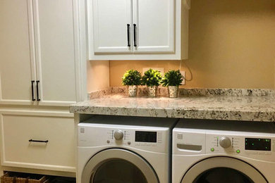 Inspiration for a mid-sized cottage single-wall travertine floor and brown floor dedicated laundry room remodel in Houston with raised-panel cabinets, white cabinets, granite countertops, brown walls, a side-by-side washer/dryer and multicolored countertops