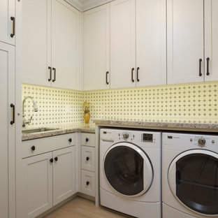 Foto di una grande sala lavanderia stile americano con lavello sottopiano, ante con riquadro incassato, ante bianche, top in granito e lavatrice e asciugatrice affiancate