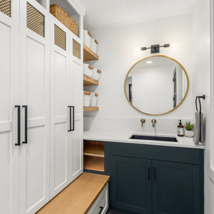 Idee per una lavanderia multiuso tradizionale di medie dimensioni con lavello da incasso, ante in stile shaker, ante blu, top in quarzo composito, pareti bianche, pavimento con piastrelle in ceramica, lavatrice e asciugatrice nascoste, pavimento grigio e top bianco