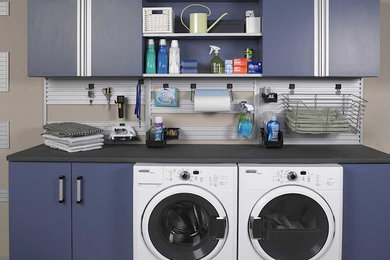 Modelo de cuarto de lavado lineal contemporáneo de tamaño medio con armarios con paneles lisos, puertas de armario azules, encimera de cuarzo compacto, paredes beige y lavadora y secadora juntas