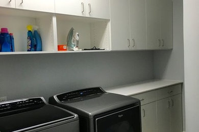 Large elegant single-wall linoleum floor utility room photo in St Louis with flat-panel cabinets, white cabinets, laminate countertops and a side-by-side washer/dryer