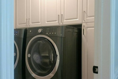 Mid-sized elegant single-wall dedicated laundry room photo in New York with raised-panel cabinets, white cabinets and a side-by-side washer/dryer