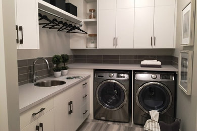Dedicated laundry room - mid-sized modern l-shaped dedicated laundry room idea in Calgary with a single-bowl sink, flat-panel cabinets, white cabinets, laminate countertops and a side-by-side washer/dryer