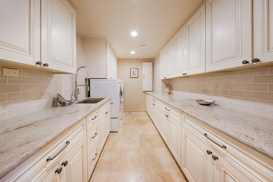 Inspiration for a large timeless galley travertine floor and beige floor dedicated laundry room remodel in Phoenix with an undermount sink, raised-panel cabinets, white cabinets, quartzite countertops, beige walls and a side-by-side washer/dryer