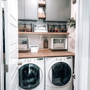 Idéer för att renovera en liten bruna linjär brunt liten tvättstuga, med grå skåp, träbänkskiva, beige väggar, klinkergolv i keramik, en tvättmaskin och torktumlare bredvid varandra och vitt golv