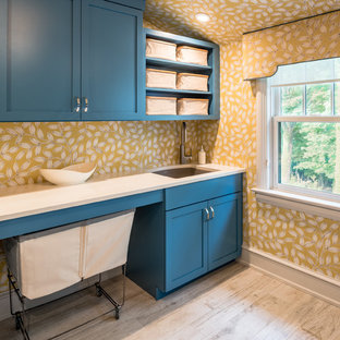 Esempio di una sala lavanderia classica con lavello sottopiano, ante in stile shaker, ante blu, pareti gialle e parquet chiaro