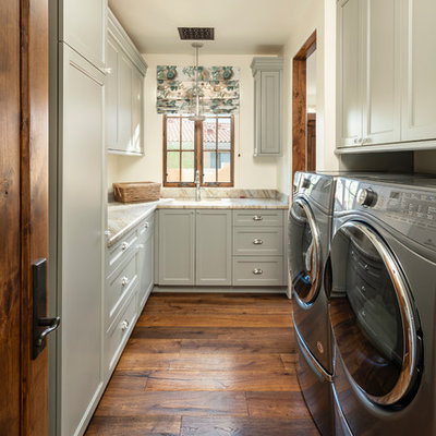 Inspiration for a timeless u-shaped medium tone wood floor and brown floor dedicated laundry room remodel in Phoenix with an undermount sink, recessed-panel cabinets, gray cabinets, a side-by-side washer/dryer, beige countertops and white walls