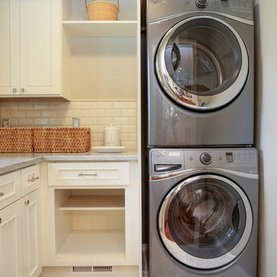 Small elegant l-shaped dedicated laundry room photo in DC Metro with white cabinets, marble countertops and a stacked washer/dryer