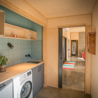 Modern inredning av ett litet parallellt grovkök, med en enkel diskho, träbänkskiva, grönt stänkskydd, stänkskydd i keramik, gröna väggar, betonggolv och grått golv
