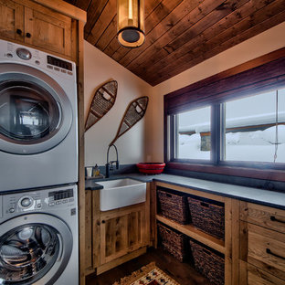 Idee per una sala lavanderia stile rurale di medie dimensioni con lavello stile country, ante lisce, top in cemento, pareti beige, pavimento in legno massello medio, lavatrice e asciugatrice a colonna e ante in legno scuro