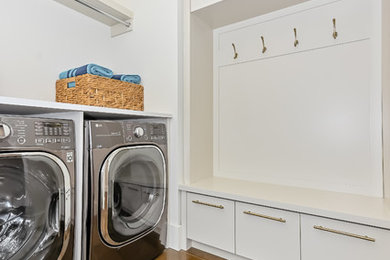 Photo of a large contemporary laundry cupboard with white cabinets, grey walls, porcelain flooring, brown floors and white worktops.