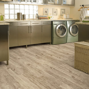 Immagine di un'ampia sala lavanderia tropicale con ante lisce, ante in acciaio inossidabile, pavimento in vinile, lavatrice e asciugatrice affiancate e pareti beige