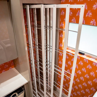 Bild på ett stort funkis vit parallellt vitt grovkök, med en nedsänkt diskho, släta luckor, grå skåp, granitbänkskiva, orange väggar, klinkergolv i keramik, en tvättmaskin och torktumlare bredvid varandra och vitt golv