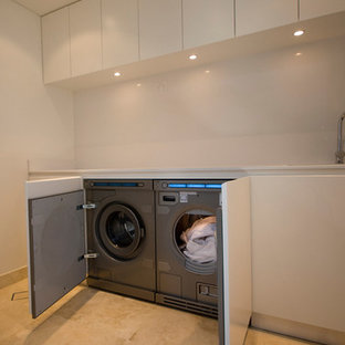 Idéer för att renovera en funkis linjär tvättstuga enbart för tvätt, med en undermonterad diskho, vita skåp, bänkskiva i kvarts, vita väggar och tvättmaskin och torktumlare byggt in i ett skåp