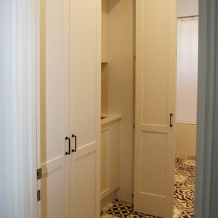 Inspiration pour une buanderie linéaire style shabby chic multi-usage et de taille moyenne avec un placard à porte shaker, des portes de placard blanches, un plan de travail en surface solide, un mur blanc, un sol en carrelage de céramique, un évier encastré, le lave-linge et le sèche-linge forment un seul appareil électroménager, un sol multicolore et un plan de travail blanc.