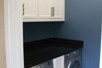 Immagine di una sala lavanderia chic di medie dimensioni con ante con riquadro incassato, ante bianche, top in superficie solida, pareti blu e lavatrice e asciugatrice affiancate