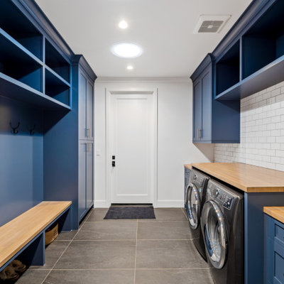 Inspiration for a huge cottage galley porcelain tile and gray floor utility room remodel in Los Angeles with an undermount sink, shaker cabinets, blue cabinets, wood countertops, white backsplash, ceramic backsplash, white walls, a side-by-side washer/dryer and beige countertops