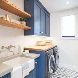 Esempio di una sala lavanderia stile marinaro con lavello stile country, ante in stile shaker, ante blu, top in legno, pareti bianche, lavatrice e asciugatrice affiancate, pavimento multicolore e top grigio