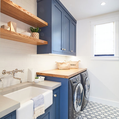 Dedicated laundry room - coastal single-wall multicolored floor dedicated laundry room idea in Los Angeles with a farmhouse sink, shaker cabinets, blue cabinets, wood countertops, white walls, a side-by-side washer/dryer and gray countertops