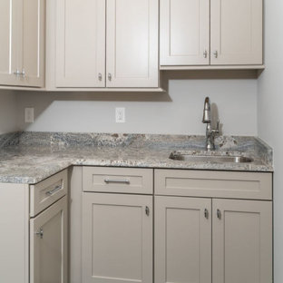 Foto di una lavanderia multiuso di medie dimensioni con lavello sottopiano, ante in stile shaker, ante beige, top in granito, paraspruzzi grigio, paraspruzzi in lastra di pietra, pareti grigie, pavimento in gres porcellanato, lavatrice e asciugatrice affiancate, pavimento nero e top grigio