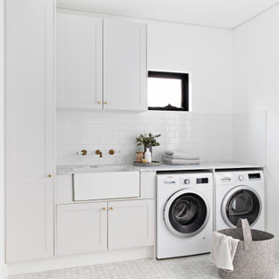 Ispirazione per una lavanderia scandinava con lavello stile country, ante in stile shaker, ante bianche, pareti bianche, pavimento in marmo, lavatrice e asciugatrice affiancate, pavimento bianco e top grigio