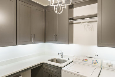 Example of a large trendy l-shaped vinyl floor dedicated laundry room design in Raleigh with an undermount sink, shaker cabinets, gray cabinets, quartzite countertops, gray walls and a side-by-side washer/dryer